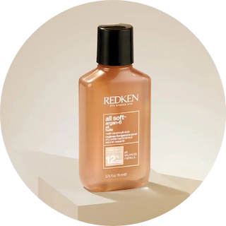 Peach-colored Redken All Soft hair product bottle with black cap.