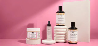 Collection of beauty or skincare products with white packaging and black caps against a pink backdrop.