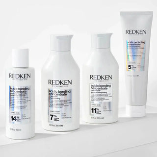 Four white Redken hair treatment bottles with blue text and different concentration percentages.