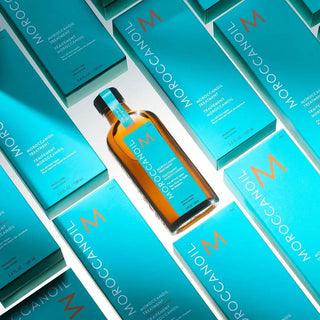 Moroccanoil hair treatment bottle with orange glass and teal label.