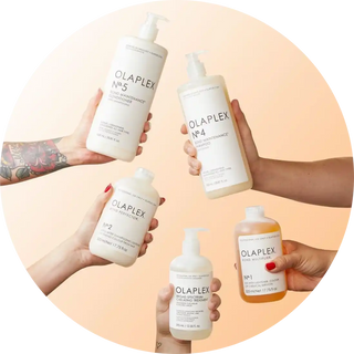 Multiple bottles of Olaplex hair care products being held by different hands.