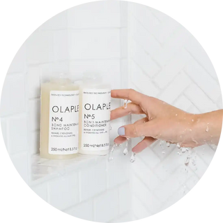 Olaplex hair treatment bottles with a hand reaching for them in water.