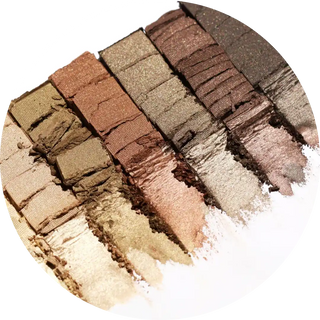 Swatches of shimmery neutral eyeshadow powders arranged in stripes.