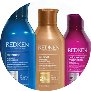 Three Redken shampoo bottles in blue, gold, and magenta colors.