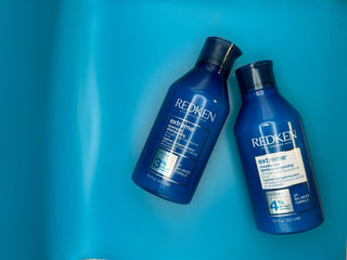 Two blue Redken hair product bottles lying side by side.